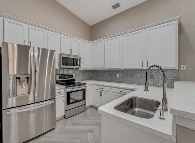 8592 Logia Cir, Boynton Beach, FL 33472 - kitchen with appliances with stainless steel finishes, a sink, white cabinetry, decorative backsplash, and vaulted ceiling
