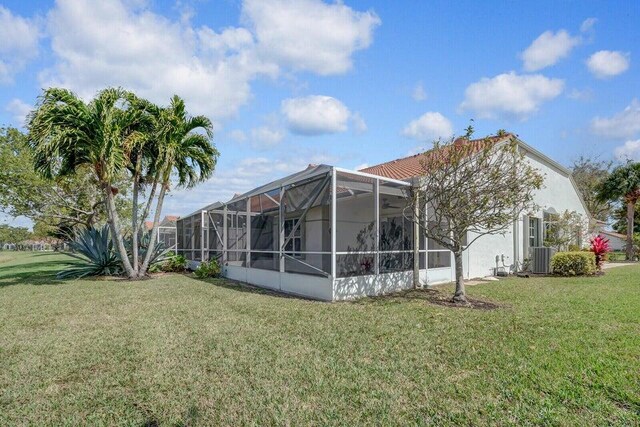 8592 Logia Cir, Boynton Beach, FL 33472 - rear view of property with a yard, glass enclosure, stucco siding, and central air condition unit