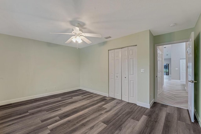 8592 Logia Cir, Boynton Beach, FL 33472 - unfurnished bedroom with dark wood-style flooring, a closet, baseboards, and ceiling fan