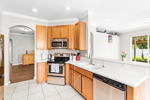 2481 SE Berkshire Blvd, Port Saint Lucie, FL 34952 - kitchen featuring appliances with stainless steel finishes, a sink, arched walkways, tasteful backsplash, and light countertops