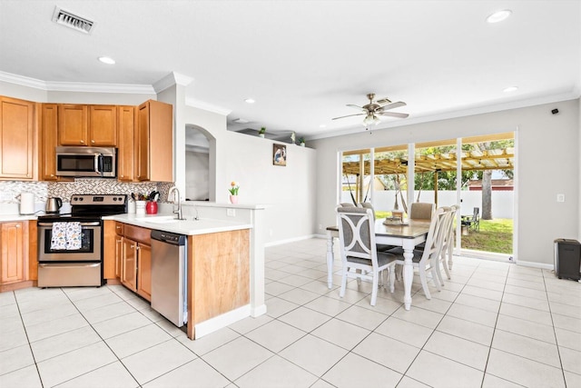 2481 SE Berkshire Blvd, Port Saint Lucie, FL 34952 - kitchen with appliances with stainless steel finishes, ornamental molding, light countertops, tasteful backsplash, and a peninsula