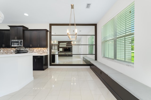 3040 Princeton Ln, Palm Beach Gardens, FL 33418 - kitchen featuring stainless steel microwave, light countertops, tasteful backsplash, decorative light fixtures, and a chandelier