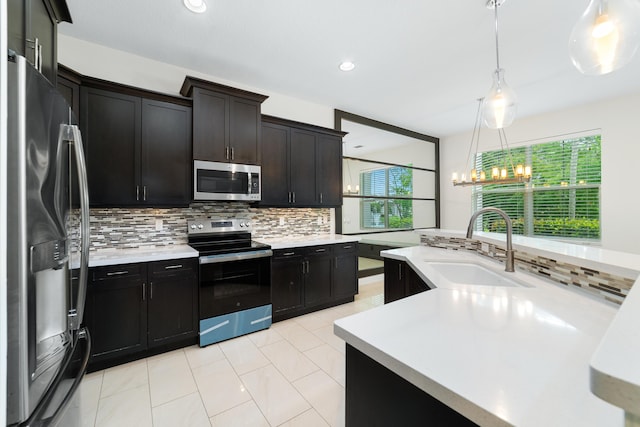 3040 Princeton Ln, Palm Beach Gardens, FL 33418 - kitchen with stainless steel appliances, a sink, decorative backsplash, light countertops, and hanging light fixtures