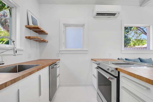 220 S L St, Lake Worth Beach, FL 33460 - kitchen with butcher block counters, stainless steel appliances, a sink, a wall unit AC, and white cabinets