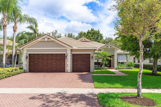 8940 New Hope Ct, West Palm Beach, FL 33411 - view of front of property with decorative driveway, an attached garage, a tile roof, a front yard, and stucco siding