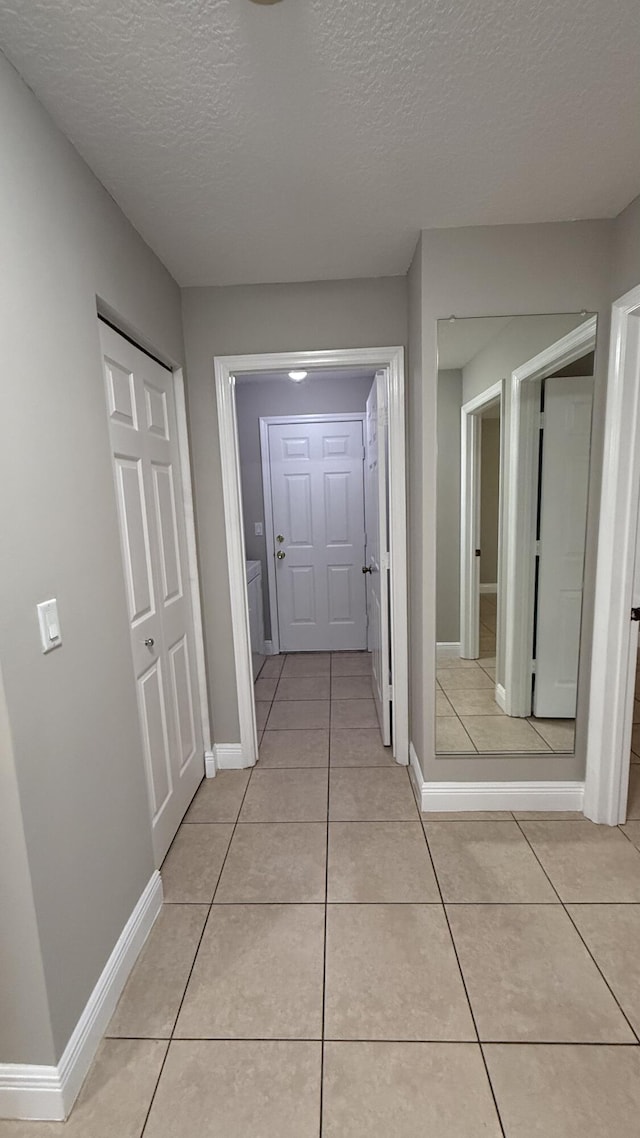 2134 SW Savage Blvd, Port Saint Lucie, FL 34953 - hall with light tile patterned floors, a textured ceiling, and baseboards
