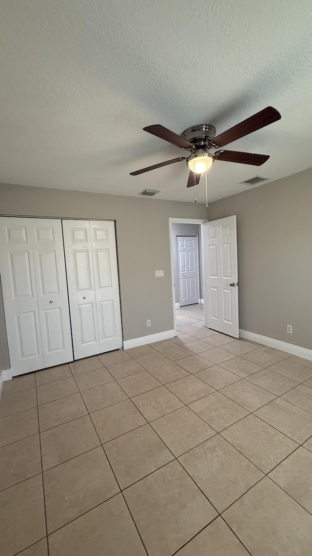 2134 SW Savage Blvd, Port Saint Lucie, FL 34953 - unfurnished bedroom featuring light tile patterned flooring, a closet, baseboards, a textured ceiling, and a ceiling fan