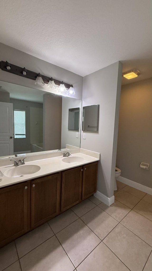 2134 SW Savage Blvd, Port Saint Lucie, FL 34953 - bathroom with tile patterned floors, double vanity, toilet, and baseboards