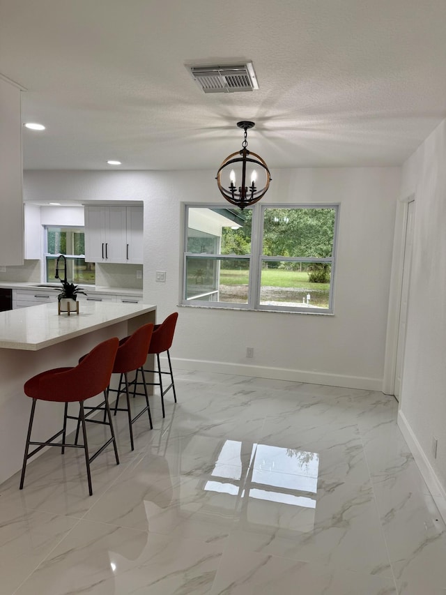 2812 F Rd, Loxahatchee Groves, FL 33470 - dining area featuring light marble finish floors, a chandelier, baseboards, healthy amount of natural light, and a textured ceiling