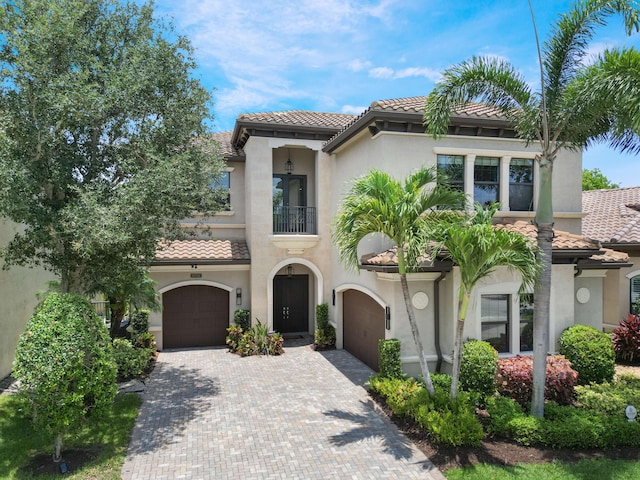 8784 Lewis River Rd, Delray Beach, FL 33446 - mediterranean / spanish home featuring a tiled roof, a balcony, stucco siding, decorative driveway, and an attached garage