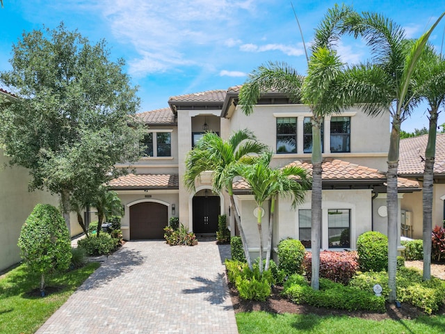 8784 Lewis River Rd, Delray Beach, FL 33446 - mediterranean / spanish-style home featuring a tiled roof, stucco siding, decorative driveway, and a garage