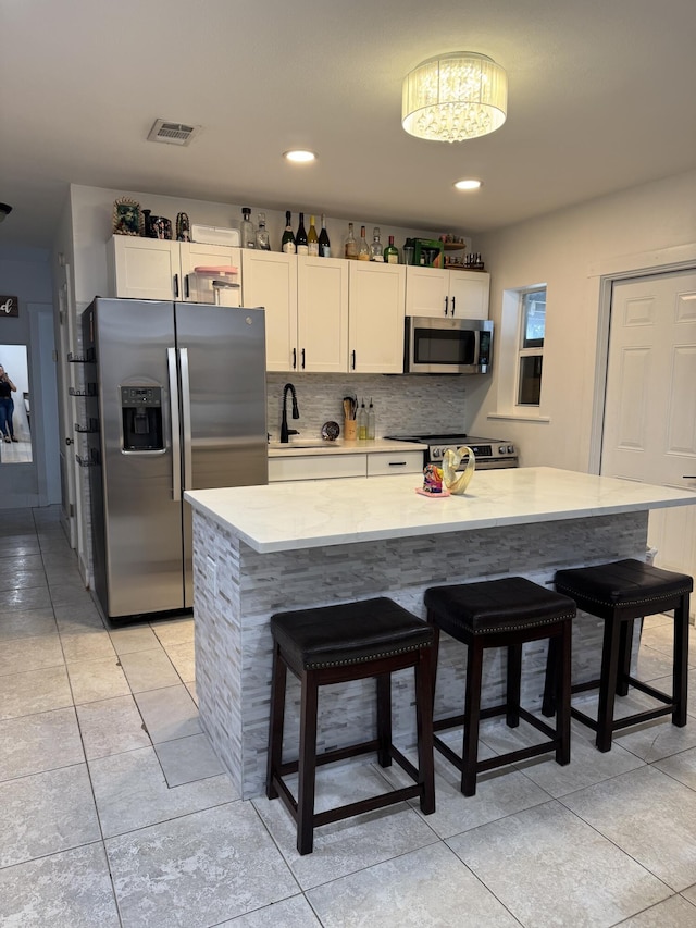 1413 S C Ter S, Lake Worth, FL 33460 - kitchen featuring stainless steel appliances, a sink, a kitchen breakfast bar, light tile patterned floors, and white cabinets