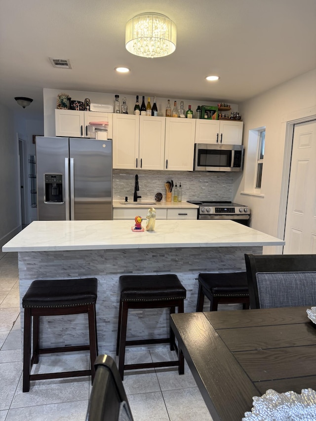 1413 S C Ter S, Lake Worth, FL 33460 - kitchen with appliances with stainless steel finishes, light tile patterned floors, white cabinetry, a kitchen bar, and recessed lighting