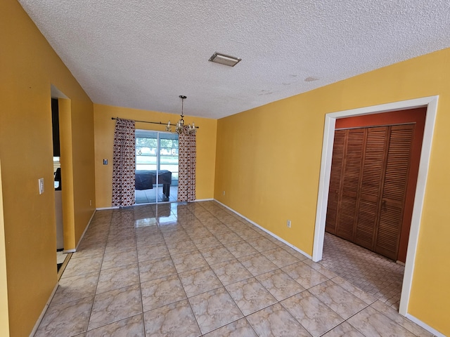 389 SE Tranquilla Ave, Port Saint Lucie, FL 34983 - empty room with a chandelier, a textured ceiling, baseboards, and light marble finish flooring