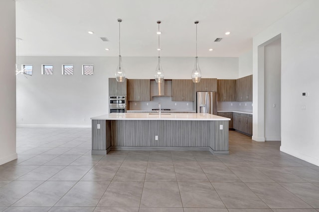 8660 W Parkland Bay Trl, Parkland, FL 33076 - kitchen featuring appliances with stainless steel finishes, wall chimney range hood, light countertops, backsplash, and a large island with sink