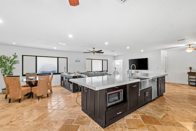 977 W Royal Palm Rd, Boca Raton, FL 33486 - kitchen featuring a ceiling fan, stone tile flooring, stainless steel microwave, open floor plan, and an island with sink