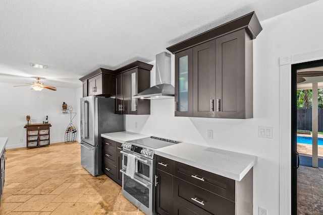 977 W Royal Palm Rd, Boca Raton, FL 33486 - kitchen featuring wall chimney exhaust hood, stainless steel appliances, stone tile floors, a ceiling fan, and glass insert cabinets