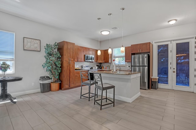 309 NE 11th Ave, Boynton Beach, FL 33435 - kitchen featuring appliances with stainless steel finishes, backsplash, a breakfast bar, pendant lighting, and brown cabinets