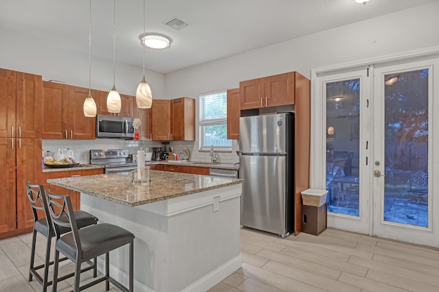 309 NE 11th Ave, Boynton Beach, FL 33435 - kitchen featuring appliances with stainless steel finishes, decorative backsplash, light stone countertops, a breakfast bar, and a kitchen island