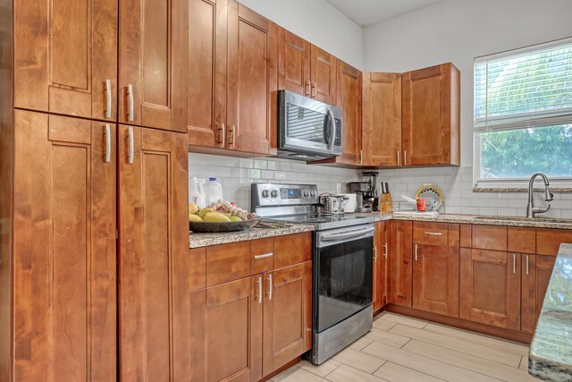 309 NE 11th Ave, Boynton Beach, FL 33435 - kitchen featuring stainless steel appliances, a sink, tasteful backsplash, and brown cabinetry