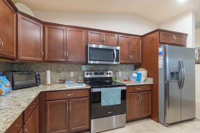 29 Mediterranean Blvd W, Port Saint Lucie, FL 34952 - kitchen featuring stainless steel appliances, decorative backsplash, vaulted ceiling, light stone counters, and light tile patterned floors