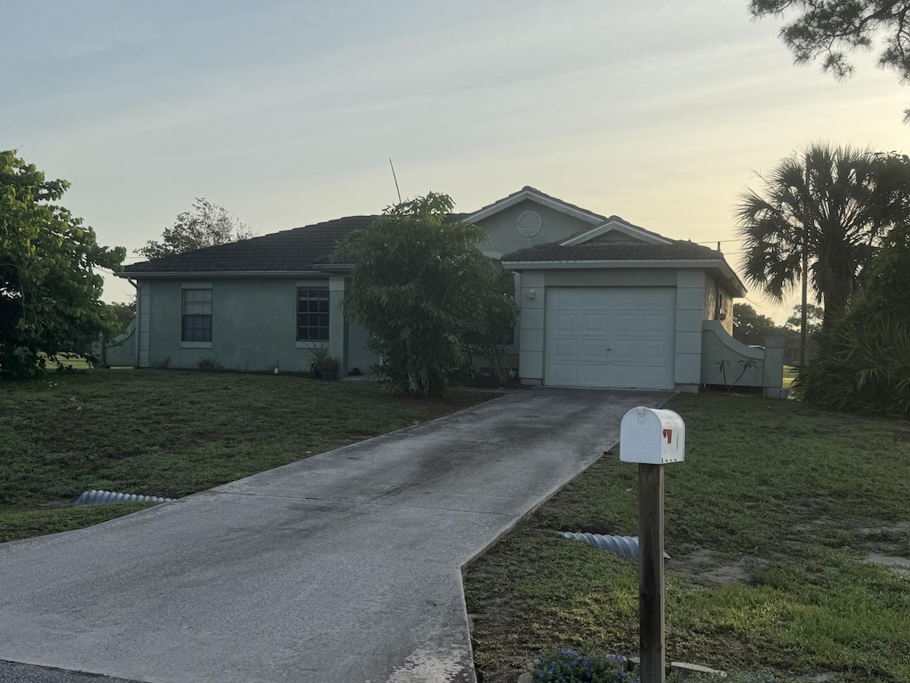 2849 SW Pierson Rd, Port Saint Lucie, FL 34953 - ranch-style house with concrete driveway, a yard, and an attached garage