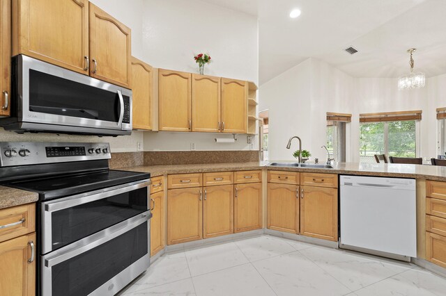 6839 Banyan Blvd, The Acreage, FL 33470 - kitchen featuring appliances with stainless steel finishes, a sink, light marble finish floors, a chandelier, and a peninsula