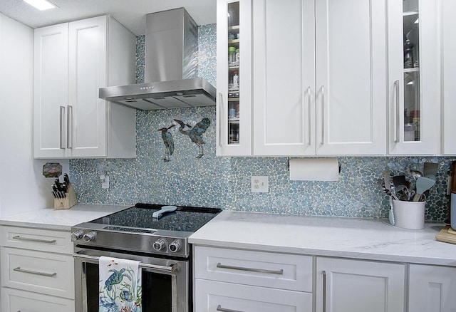 1177 Bayshore Dr Unit 207, Fort Pierce, FL 34949 - kitchen with wall chimney range hood, stainless steel electric stove, white cabinetry, and glass insert cabinets