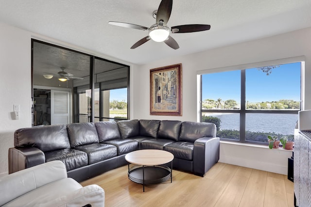 2850 Carambola Cir S Unit 19121, Coconut Creek, FL 33066 - living area featuring a ceiling fan, plenty of natural light, light wood-type flooring, a water view, and a textured ceiling