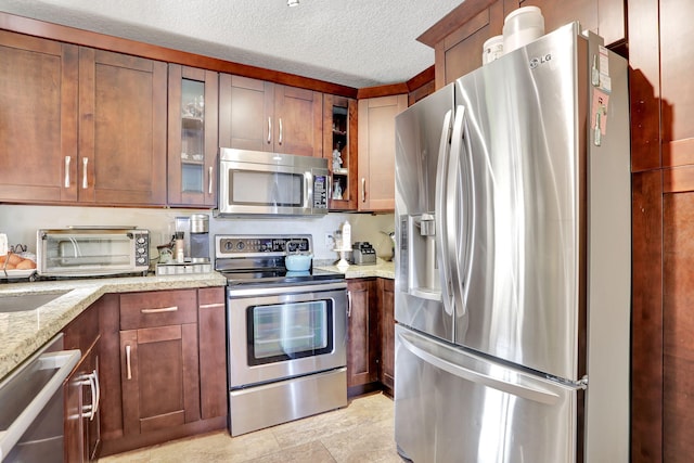 2850 Carambola Cir S Unit 19121, Coconut Creek, FL 33066 - kitchen featuring appliances with stainless steel finishes, light stone counters, a textured ceiling, and glass insert cabinets