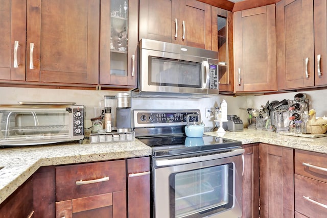 2850 Carambola Cir S Unit 19121, Coconut Creek, FL 33066 - kitchen with appliances with stainless steel finishes, glass insert cabinets, light stone countertops, and brown cabinets