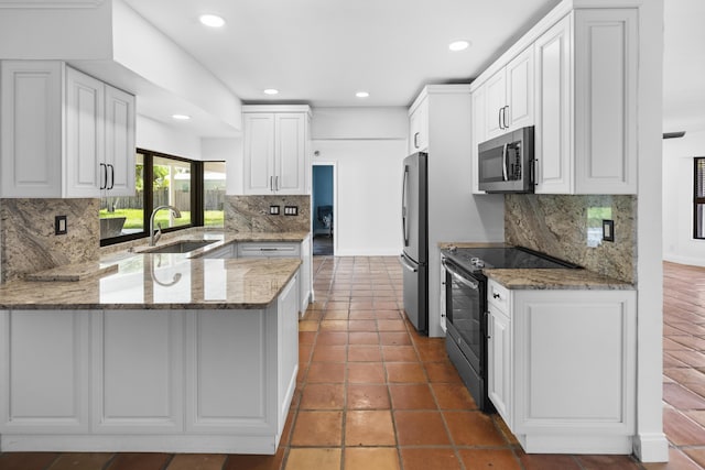 1318 NW 4th St, Boca Raton, FL 33486 - kitchen featuring appliances with stainless steel finishes, a peninsula, tasteful backsplash, recessed lighting, and light stone counters