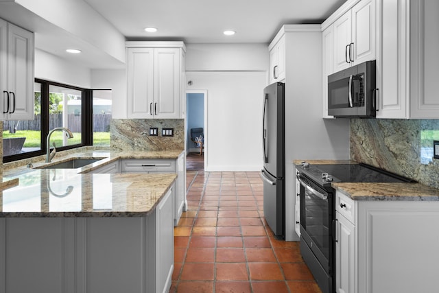 1318 NW 4th St, Boca Raton, FL 33486 - kitchen with stainless steel appliances, a peninsula, white cabinetry, tasteful backsplash, and light stone countertops