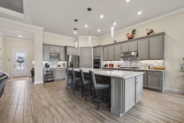 11620 Sally Ann Dr, Palm Beach Gardens, FL 33412 - kitchen featuring gray cabinets, beverage cooler, under cabinet range hood, appliances with stainless steel finishes, and decorative backsplash