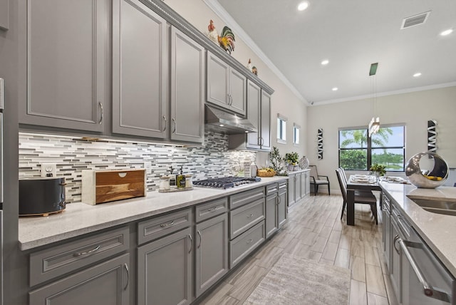 11620 Sally Ann Dr, Palm Beach Gardens, FL 33412 - kitchen featuring under cabinet range hood, gray cabinetry, stainless steel appliances, backsplash, and crown molding