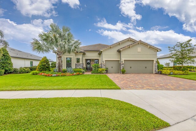 11620 Sally Ann Dr, Palm Beach Gardens, FL 33412 - view of front facade with decorative driveway, stucco siding, a front yard, and an attached garage