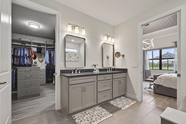 11620 Sally Ann Dr, Palm Beach Gardens, FL 33412 - ensuite bathroom featuring double vanity, tile patterned flooring, a spacious closet, and baseboards