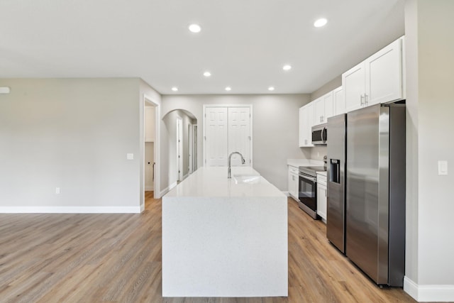 518 Scodella St SW, Palm Bay, FL 32908 - kitchen with stainless steel appliances, a sink, white cabinets, arched walkways, and light wood finished floors