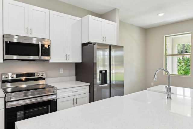 518 Scodella St SW, Palm Bay, FL 32908 - kitchen with stainless steel appliances, a sink, white cabinetry, light stone counters, and recessed lighting