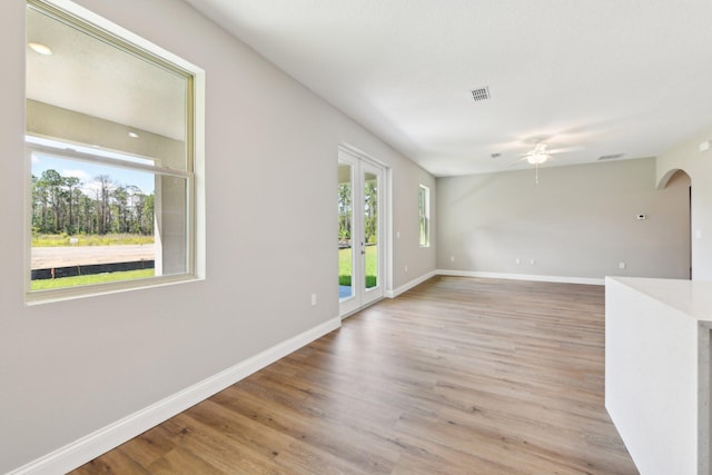 518 Scodella St SW, Palm Bay, FL 32908 - empty room with ceiling fan, arched walkways, light wood-type flooring, baseboards, and french doors