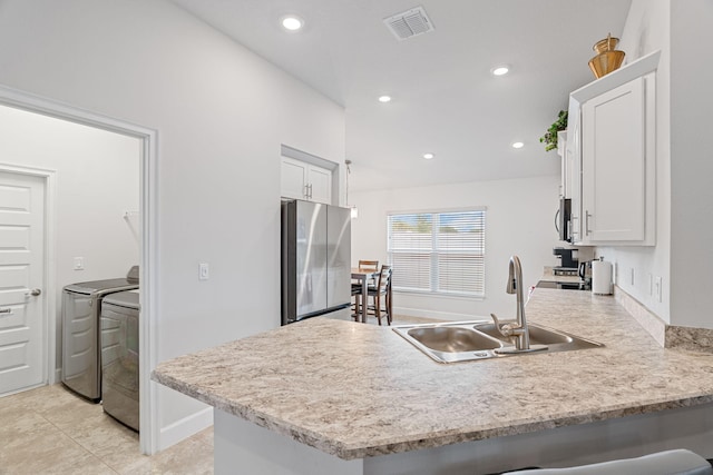 5309 Vespera St, Fort Pierce, FL 34951 - kitchen with stainless steel appliances, washing machine and dryer, a sink, a peninsula, and white cabinetry