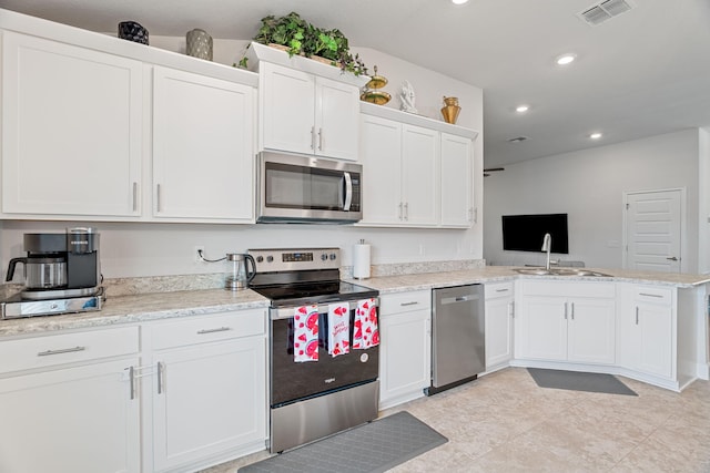 5309 Vespera St, Fort Pierce, FL 34951 - kitchen featuring appliances with stainless steel finishes, white cabinets, a sink, a peninsula, and recessed lighting