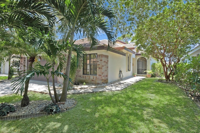 4560 Sherwood Forest Dr, Delray Beach, FL 33445 - view of side of home with a yard, brick siding, stucco siding, and a tile roof