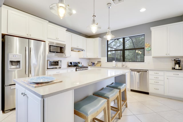 568 SE Monet Dr, Port Saint Lucie, FL 34984 - kitchen with stainless steel appliances, under cabinet range hood, a sink, a kitchen island, and decorative backsplash