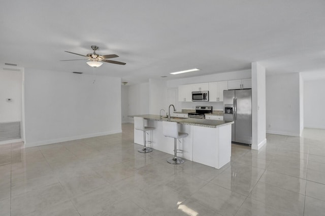 6650 NW 22nd Ct, Margate, FL 33063 - kitchen with stainless steel appliances, a ceiling fan, a kitchen breakfast bar, white cabinets, and a center island with sink