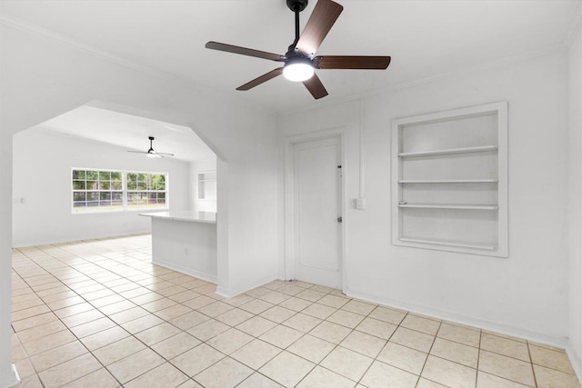7802 Miramar Ave, Fort Pierce, FL 34951 - unfurnished room featuring ceiling fan, built in shelves, crown molding, light tile patterned floors, and arched walkways