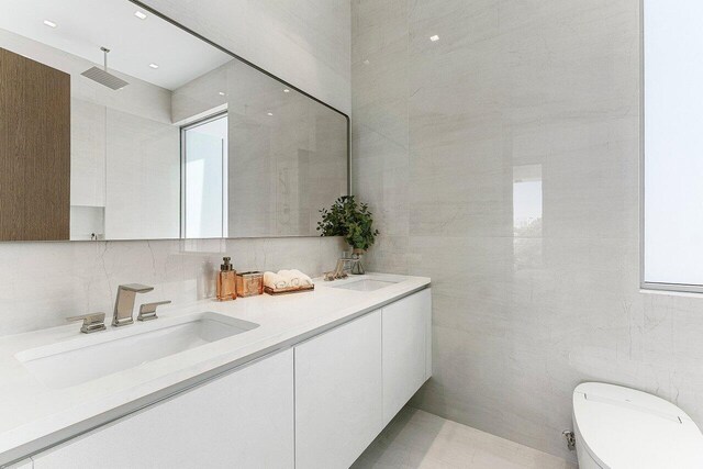 246 NE 6th Ave Unit Ph1, Delray Beach, FL 33483 - bathroom with tile walls, double vanity, toilet, and backsplash