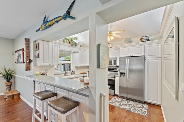 9674 Dogwood Ave, Palm Beach Gardens, FL 33410 - kitchen with stainless steel appliances, a breakfast bar area, light wood-style flooring, and white cabinetry