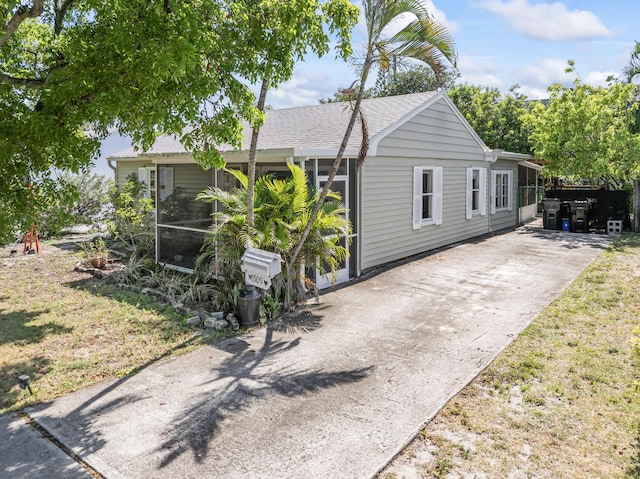 1509 N N St, Lake Worth Beach, FL 33460 - view of front of house featuring concrete driveway, roof with shingles, and a sunroom