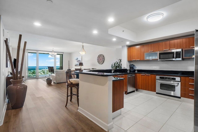 2640 Lake Shore Dr Unit 2409, Riviera Beach, FL 33404 - kitchen featuring stainless steel appliances, modern cabinets, brown cabinetry, dark countertops, and recessed lighting